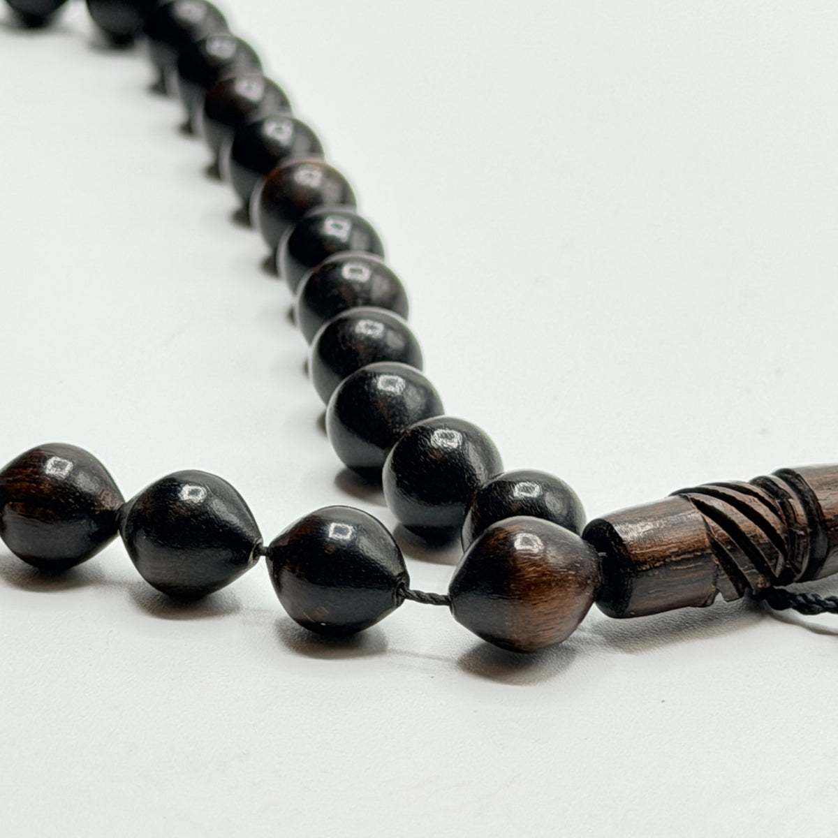 Close view of polished ebony prayer beads and carved wooden imame