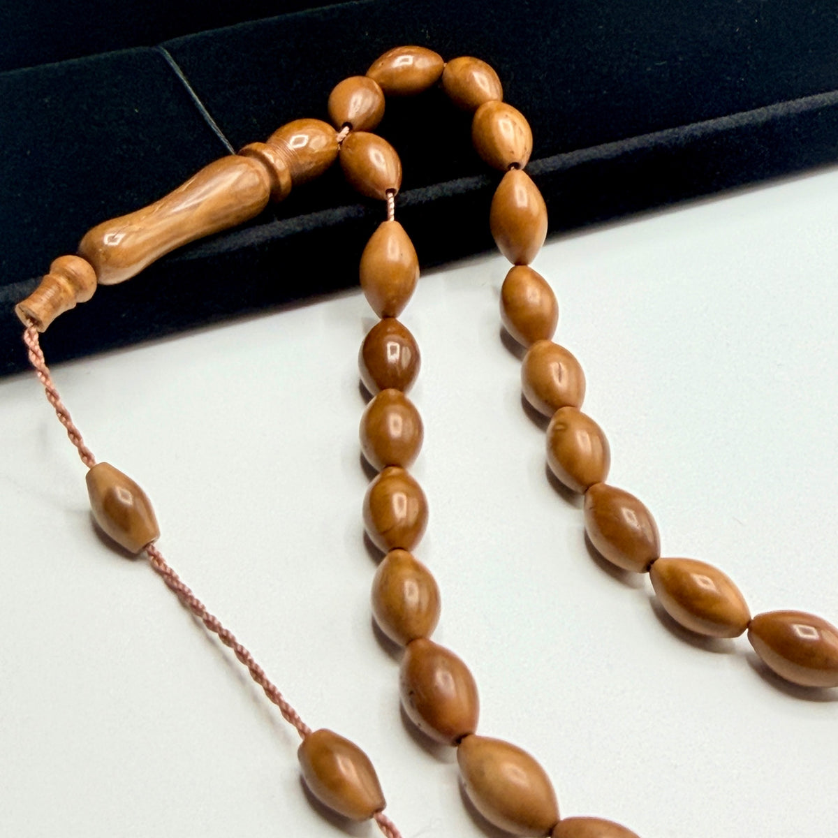 Close view of polished oval Kuka wood beads and carved imame