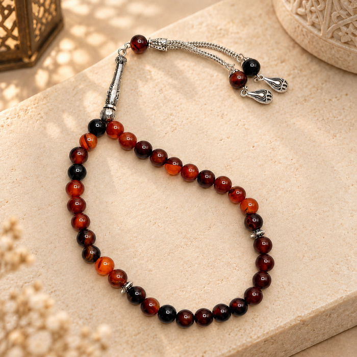 Noir Aqeeq 33 bead Tasbih styled in warm natural light