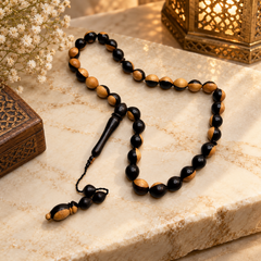 Handmade two-tone ebony wood 33 bead tasbih on a cream studio background