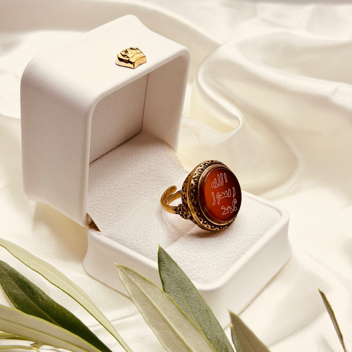 Angled view of the red aqeeq ring and its antique gold tone setting
